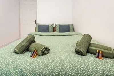 a bedroom with a large bed with green sheets and pillows at Kapana Beat 2-bedroom apt. Top Center in Plovdiv