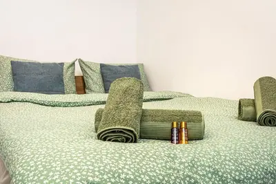 a bed with green blankets and pillows on it at Kapana Beat 2-bedroom apt. Top Center in Plovdiv
