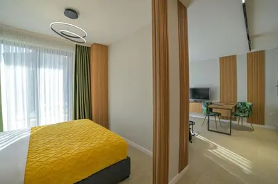 a bedroom with a bed and a desk and a television at ARHEYA 3 apart АРХЕЯ 3 апартамент за гости in Karlovo