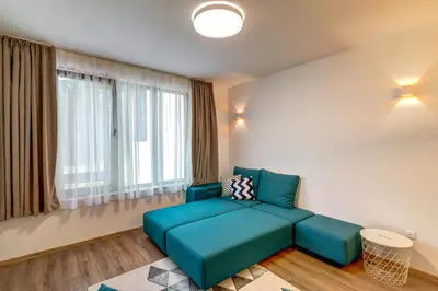 a living room with a blue couch in front of a window at N.Joy Holiday Apartment 532 by Oak Residence in Smolyan