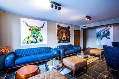 a living room with a blue couch and some paintings at N.Joy Holiday Apartment 417 by Sunny Hills in Pamporovo