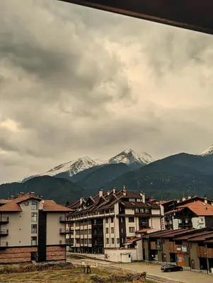 a city with snow capped mountains in the background at Great View Apartment near Gondola in Bansko