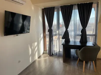 a room with a desk and a television on a wall at ZaraApartHotel in Sofia