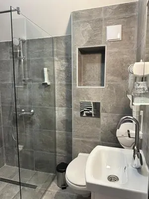 a bathroom with a shower and a toilet and a sink at Бутик хотел ресторант брасери и релакс зона Сажитариус in Kyustendil