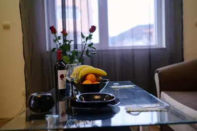 a glass table with a bowl of fruit and a bottle of wine at Cozy & Delightful Apart & AUBG & Free Garage Parking in Blagoevgrad