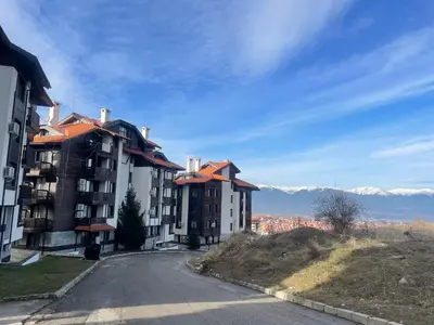a building on a hill with mountains in the background at Royal Park SP apartments-Bansko in Bansko