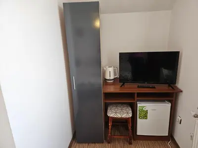 a room with a television and a desk with a small refrigerator at Cтаи за гости Бърдареви in Bansko