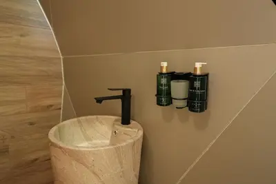 a bathroom with a sink with a faucet and two bottles at Glass Domes - by The Wind Mills Hydropark in Gorna Malina