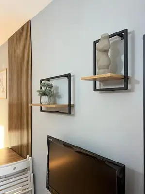 a flat screen tv sitting on a wall with shelves at Cozy Boutique Apartment in Plovdiv in Plovdiv
