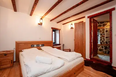 a bedroom with a bed with white sheets and a window at Къща за гости Родопчани in Smolyan