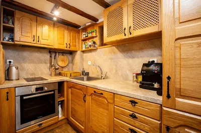 a kitchen with wooden cabinets and a sink and a microwave at Къща за гости Родопчани in Smolyan