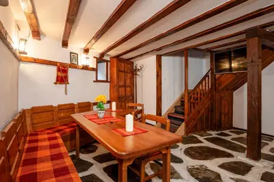 a dining room with a wooden table and chairs at Къща за гости Родопчани in Smolyan