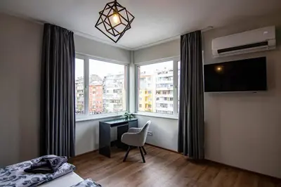 a bedroom with a bed and a desk and a window at Jungle apartment in the center in Sofia