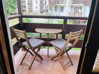 a pair of chairs and a table on a balcony at Mountain Cedar Pine 1 BR Apt near Ski Gondola in Bansko