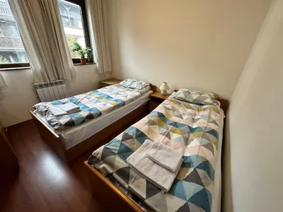 two twin beds in a room with a window at Gramadeto two bedroom apartment next to Gondola in Bansko