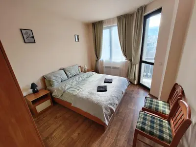 a bedroom with a bed and a large window at Уютная квартира в комплексе Snow Lodge in Bansko