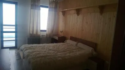a bedroom with a large white bed with a window at Vadjo Apartments in Complex Stenata Pamporovo in Pamporovo