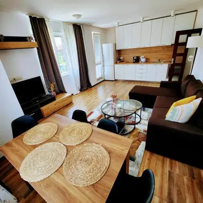 a living room with a wooden table and a kitchen at Aпартамент-София/ Newhome lux apartment in Sofia