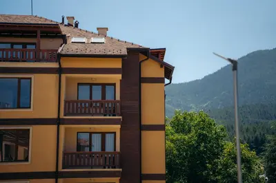 a yellow building with balconies and a street light at Pirin Sense apartment A11 in Bansko