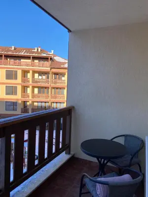a balcony with a table and chairs and a building at Pirin Sense apartment A11 in Bansko
