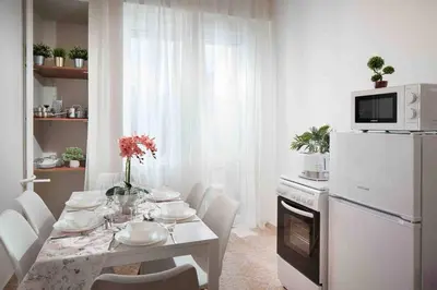 a white kitchen with a table and a white refrigerator at National Palace Of Culture 1 Step Away! in Sofia