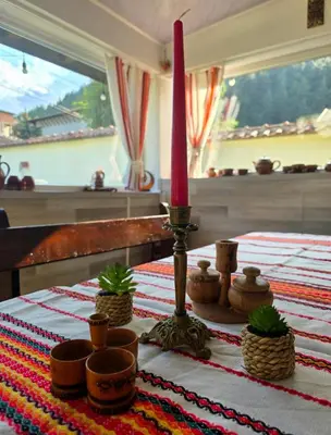 a candle sitting on top of a table with plants at Guest House Freya in Beli Iskar