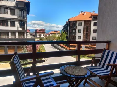 two chairs and a table on a balcony with a view at TO FOUR+2 PREDELA 1 in Bansko