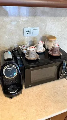 a microwave with cups and plates on top of it at ELEA Apartment Mountain Lodge Pamporovo in Pamporovo