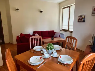 a living room with a table and a couch at Cedar Heights Cozy Apartments in Pamporovo