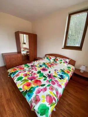 a bed with a floral comforter in a bedroom at Cedar Heights Cozy Apartments in Pamporovo