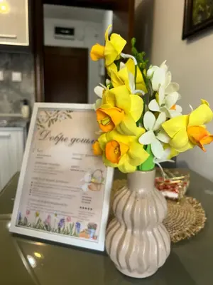 a vase filled with yellow and white flowers on a table at Apartament Kamarashki in Troyan