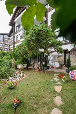 a garden in front of a building with a tree at Garden apartment Aspen Suites A008 in Bansko