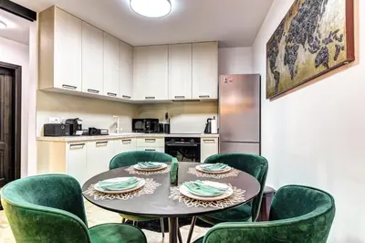 a kitchen with a table and green chairs at Boutique Apartment DOLCHE VITA in Smolyan