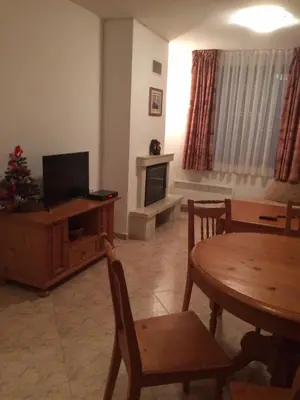 a living room with a television and a table with chairs at Скиелит 5 in Pamporovo