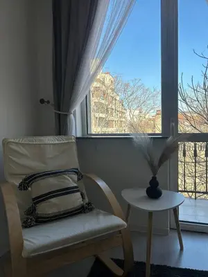 a chair and a table in a room with a window at Pirostka Vintage Room in Sofia