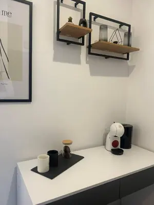 a white counter with cups and shelves on a wall at Pirostka Vintage Room in Sofia