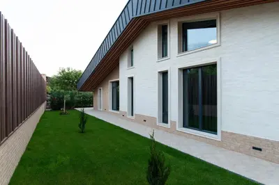 a house with a green lawn next to a building at Alpine Bell Villa in Banya