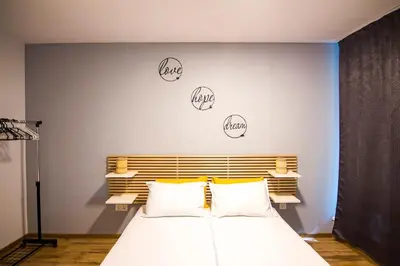 a bedroom with a large white bed with letters on the wall at Аpartment near Sofia airport in Sofia