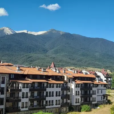 a large apartment building with mountains in the background at Belvedere K203 in Bansko