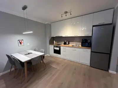 a kitchen with white cabinets and a table and a refrigerator at Boston Cozy Elegant Family Apt w Parking Near NSA in Sofia