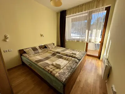 a bedroom with a bed and a large window at Pine Tree one bedroom apartment in Bansko