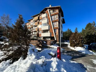 a apartment building with a red fire hydrant in the snow at Pine Tree one bedroom apartment in Bansko