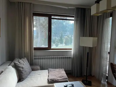 a living room with a white couch and a window at Nikol 3 SPA CLUB BOR in Velingrad
