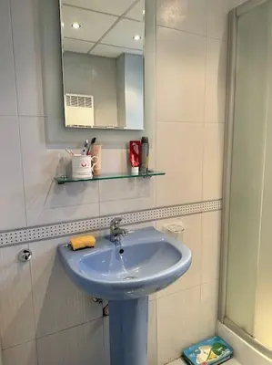 a bathroom with a blue sink and a mirror at Уникален апартамент с изглед към планината in Bansko