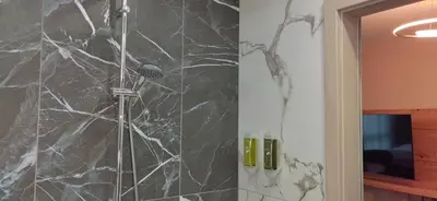 a shower in a bathroom with a black marble wall at Apartmenthaus Oborishte in Panagyurishte
