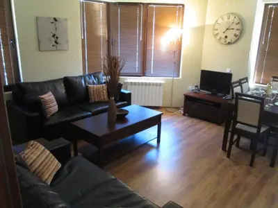 a living room with a couch and a table and a clock at Comfort Private Apartments in Bansko