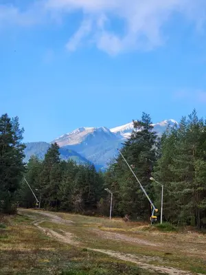 a person standing on a dirt road with mountains in the background at One Bedroom Apartment Pirin Lodge in Bansko