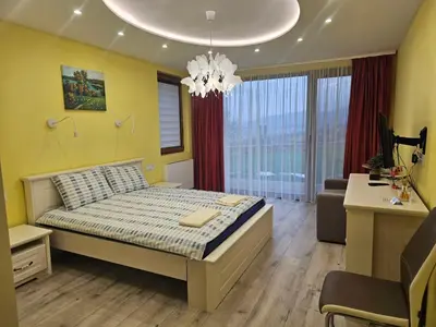 a bedroom with a bed and a desk and a chandelier at Relax Srednogorska Panorama in Smolsko