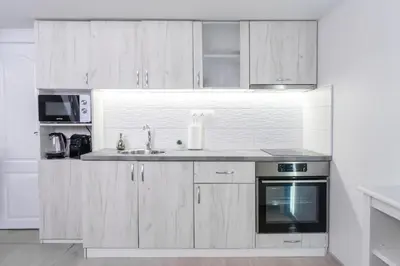 a kitchen with white cabinets and a sink and a stove at Déja Blue Old City Center studio. in Sofia