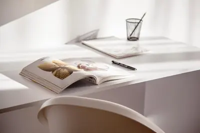 a book on a table with a pen and a glass at White Сozy Studio A next to the Gondola in Bansko